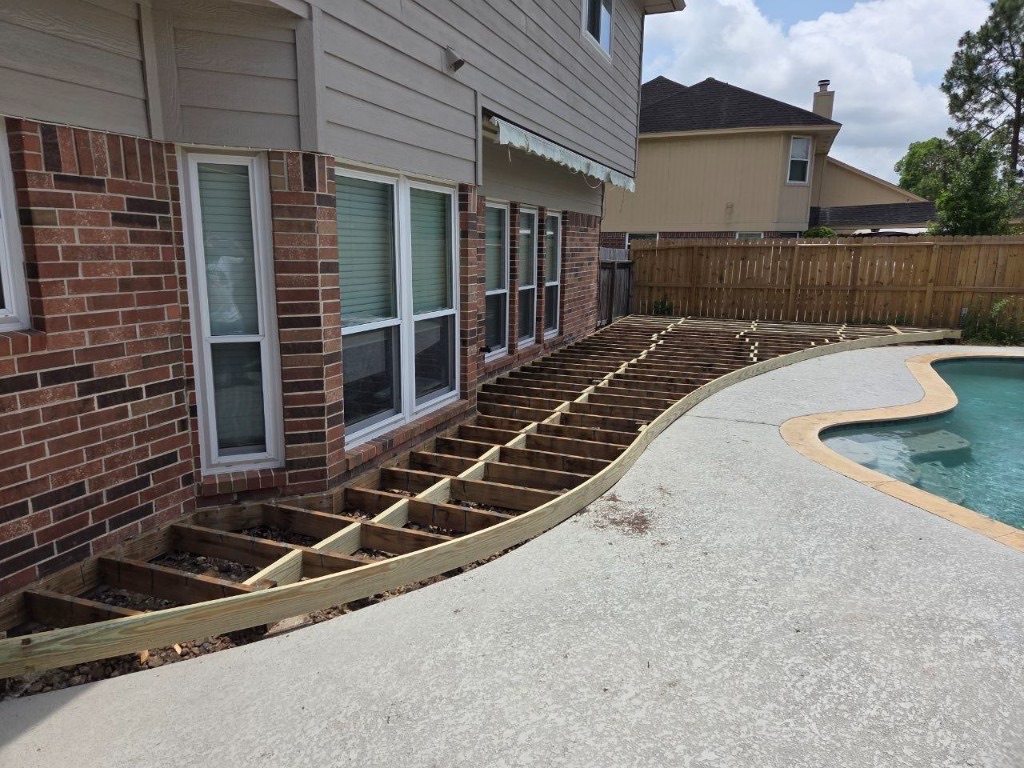 Curved deck framing under construction beside the pool